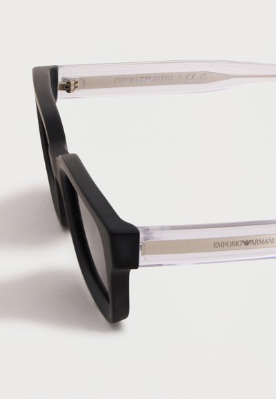 Μαύρο ορθογώνιο σκελετό γυαλιών με διαυγή διαφανή βραχίονες, διακοσμημένους με ασημένιες μεταλλικές λεπτομέρειες και λογότυπο Emporio Armani στο πλάι.