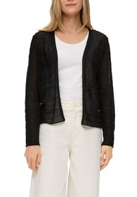 Schwarze, transparente Strickjacke mit horizontalem Streifenmuster, offener Front, langen Ärmeln und lockerer Passform, getragen über einem weißen T-Shirt und hellen Hosen.