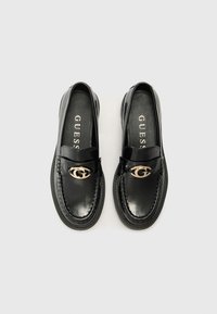 Zwarte patenten loafer met een ronde neus, gestikte details en een gouden 'G' logo-accent aan de voorkant. Zachte binnenvoering.