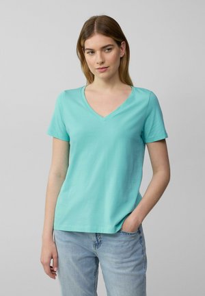 V-hals, kortemouwen t-shirt in licht turquoise, gemaakt van zachte katoen, met een relaxte pasvorm en een nette zoom, gedragen met lichtblauwe jeans.