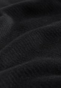 Tessuto nero con una texture morbida e liscia, caratterizzato da un sottile motivo a costine e pieghe delicate, che indicano un materiale leggero.