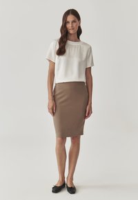 Bílý top s krátkým rukávem, vysoký výstřih, v kombinaci s těsnou hnědou tužkovou sukní. Černé baleríny dotvářejí outfit. Jednoduché a neutrální barvy.