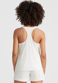 White tank top featuring a racerback design, smooth cotton texture, and a straight hem, paired with white shorts.