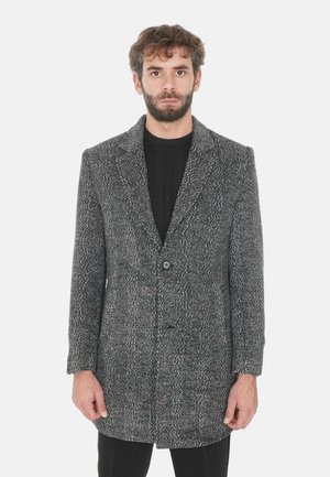 Cappotto lungo da uomo in tweed con motivo a spina di pesce in nero e grigio. Collo a scialle, chiusura con un solo bottone e taglio dritto con tessuto testurizzato.