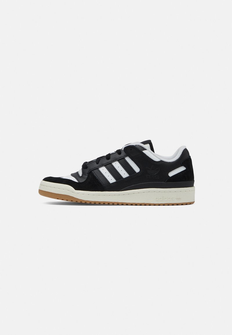 Zwarte suède en leren sneaker met witte strepen, ronde neus en gumrubberen buitenzool. Beschikt over een gewatteerde kraag en een gebrandmerkte hielstrip.