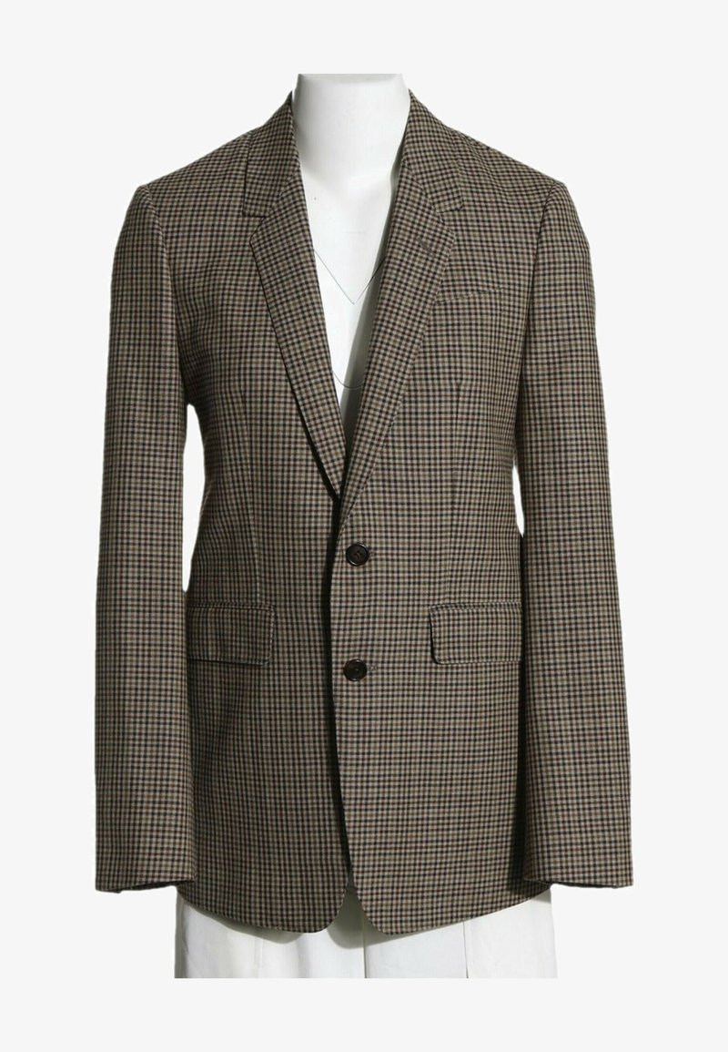 Blazer pour homme taillé avec motif petit carreau marron et beige, deux boutons noirs et poches à rabat sur torse de mannequin blanc.