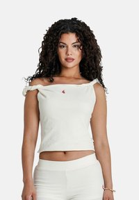 Off-white, off-shoulder top van gestructureerde stof met opgerolde mouwen en een klein rood logo op de borst.