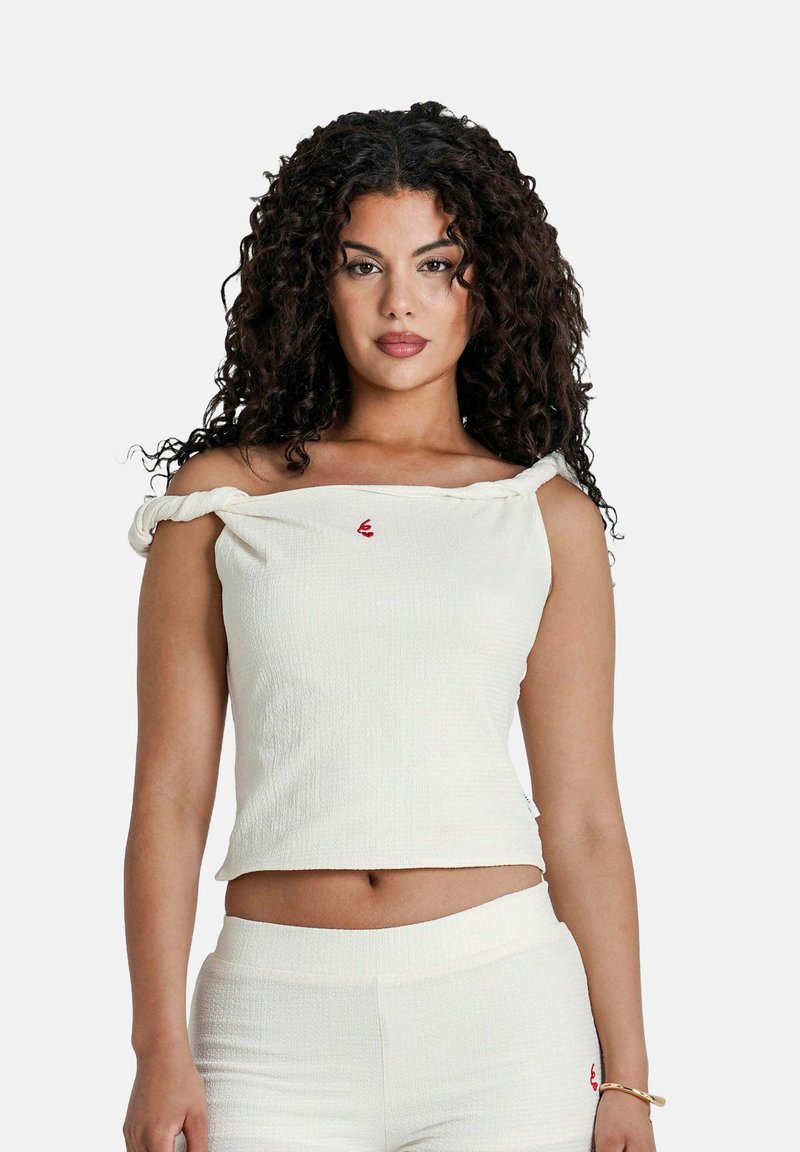 Off-white, off-shoulder top van gestructureerde stof met opgerolde mouwen en een klein rood logo op de borst.