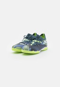 Scarpe sportive con una tomaia in mesh blu navy, accenti verde neon e motivi a righe dinamiche. Presentano una suola in gomma testurizzata per garantire grip.