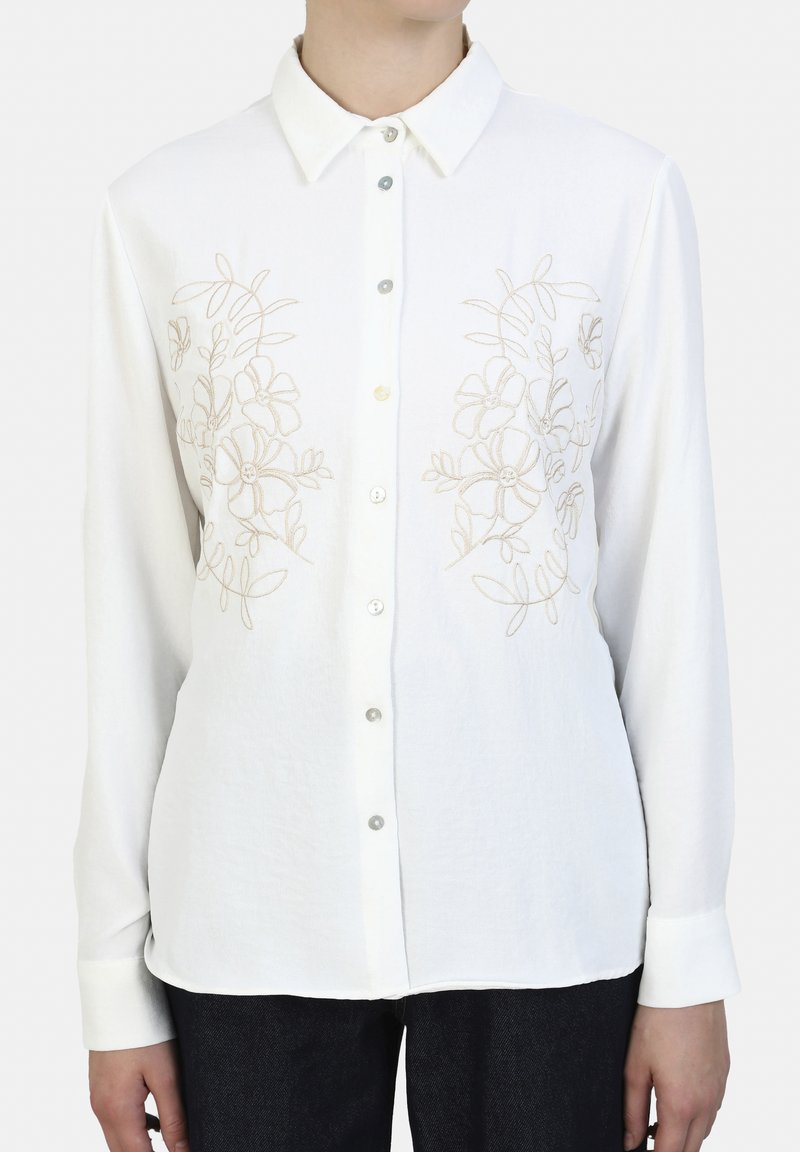 White long-sleeve shirt with a button-up front, featuring beige floral embroidery on the chest. Soft fabric with a classic collar and cuffs.