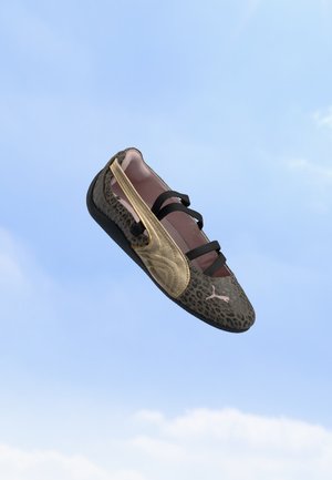 Chaussure plate imprimé léopard unique avec un détail doré sur le côté et des brides noires flottant sur un fond de ciel bleu.