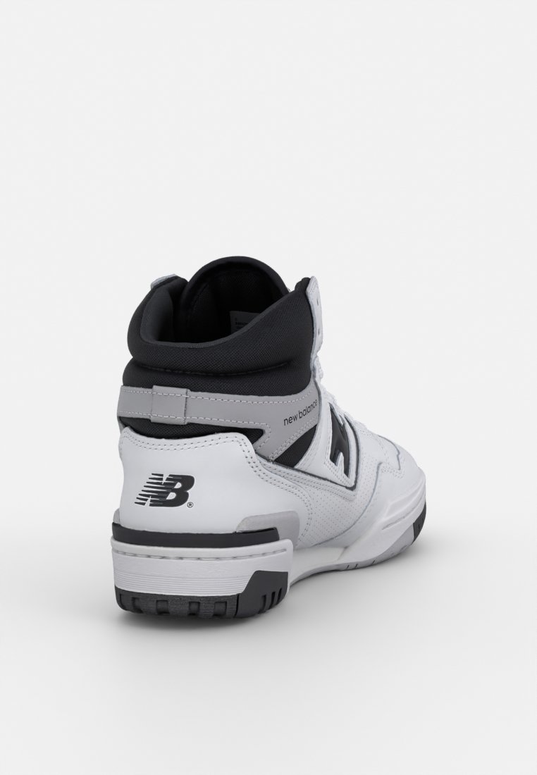 Baskets montantes blanches et noires avec une tige en cuir, un col rembourré et des accents texturés. Comprend un logo bien visible près du talon.