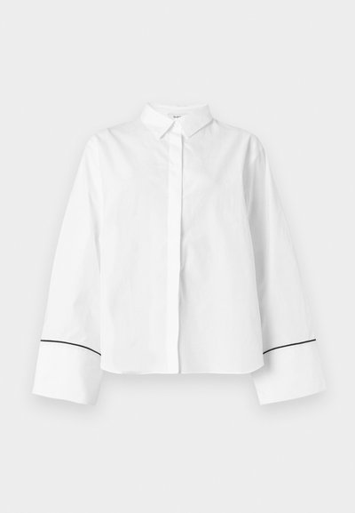 Chemise blanche à manches longues boutonnée, col pointu, larges poignets avec fine bordure noire près des extrémités, devant uni et coupe décontractée.