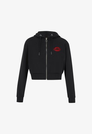 Hanorac scurt negru cu fermoar argintiu, șnururi și un detaliu brodat cu buze roșii pe partea stângă a pieptului. Fabricat dintr-un material texturat, moale.