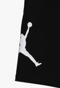 Svarta basketshorts med en framträdande vit Jumpman-logotyp på sidan. Tillverkade av mjukt, flexibelt tyg med en slät yta.