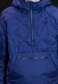 Navyblå tröja med halvdragkedja, strukturerat mönster, justerbar huva och framficka med dragkedja. Slät textur, lätt material.