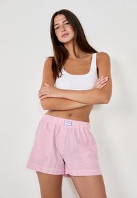 Rood-witte gestreepte boxershorts met een elastische tailleband, voorzien van een klein label. De stof ziet er zacht en lichtgewicht uit.