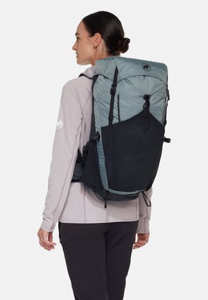 Backpack featuring a light blue top section with mesh accents, dark blue lower half, adjustable straps, and a cinched closure.