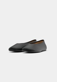 Scarpe nere flat con una finitura liscia e opaca. Design a punta e stile minimalista. Interno morbido per il comfort.