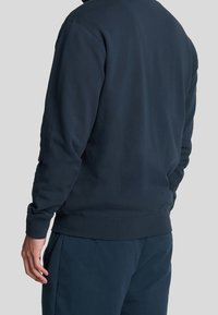 Navy blå sweatshirt med en rund halsudskæring og lange ærmer. Har ribbede manchetter og kant, lavet i blødt, struktureret stof.