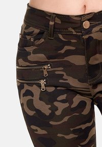 Camo-Muster-Hosen in Grüntönen und Braun, mit zwei Reißverschlusstaschen an den Seiten und einer taillierten Passform.