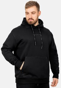 Felpa nera in cotone con tasca a marsupio frontale, cappuccio con cordoncino e logo ricamato sul petto. Presenta polsini e orlo a coste.