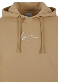 Beige hettegenser med snor og hvit brodert logo. Mykt stoff med en glatt tekstur og avslappet passform.