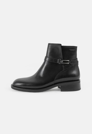 Černá kožená kotníková bota s kulatou špičkou, matným povrchem, dekorativním detailem na pásku a nízkým blokovým podpatkem. Boční zip pro snadné obutí.