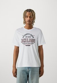 White cotton t-shirt featuring a graphic print with "JACK & JONES" text in dark blue and red, short sleeves, and a crew neckline.