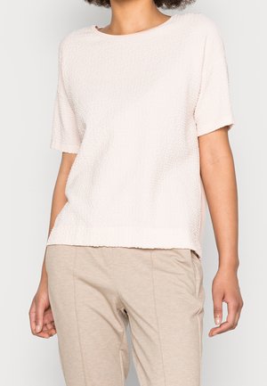 Vaaleanpunainen lyhythihainen paita, jossa on hieman väljää, teksturoitua kangasta. Pyöreä pääntie ja suora helma, valmistettu pehmeästä ja hengittävästä materiaalista.