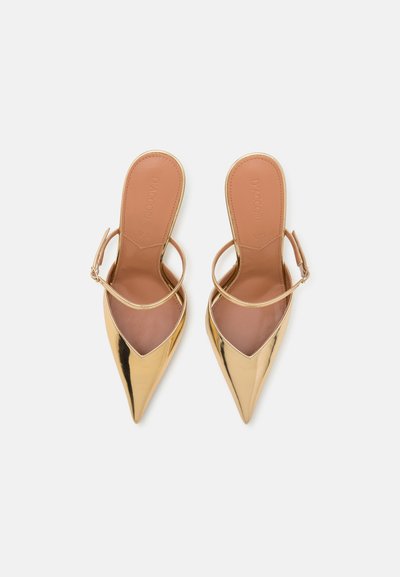 Zapatos dorados de charol, con punta afilada y tiras tipo slingback, que tienen una única banda y plantillas en tono beige; diseño elegante y textura suave.