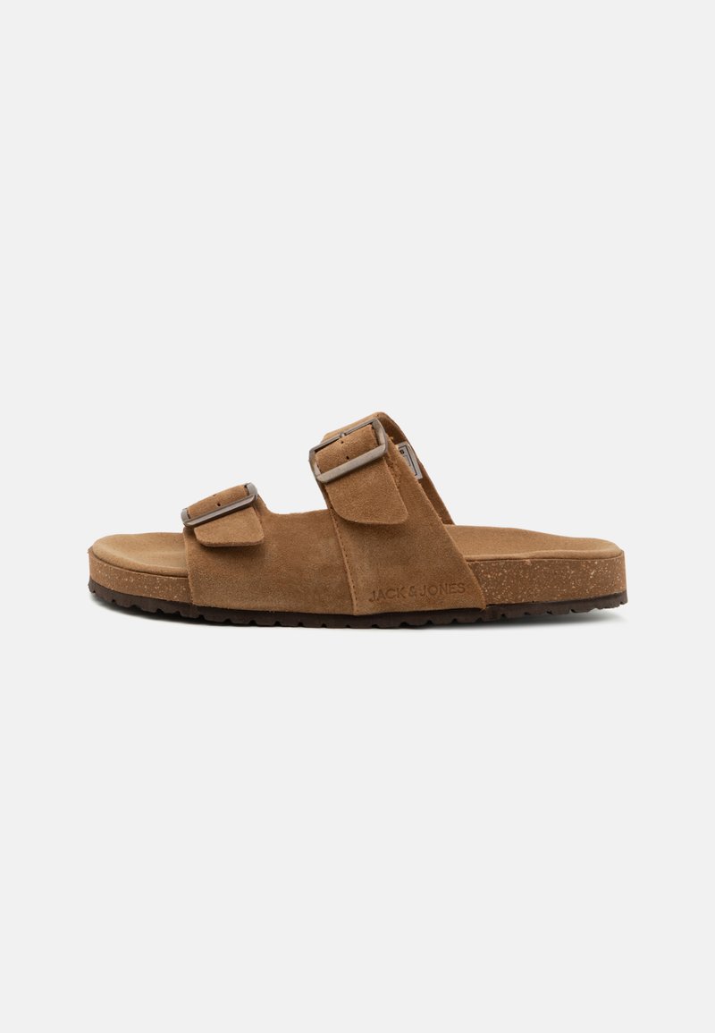 Sandalias de ante marrón con dos correas ajustables y hebillas metálicas. Plantilla de corcho y suela de goma texturizada. Presenta el logo de la marca en el lateral.