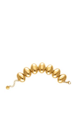 Pulsera de oro con siete grandes cuentas ovaladas conectadas por pequeños eslabones y un cierre con una cadena extensora sobre un fondo blanco.