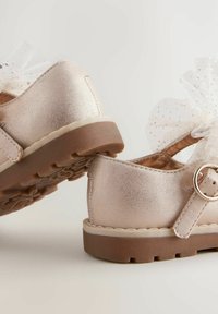 Metallic roségoldene Schuhe mit einer weichen Textur, einem großen Tüllbogen, einem Schnallenriemen und einer strapazierfähigen braunen Gummisohle.