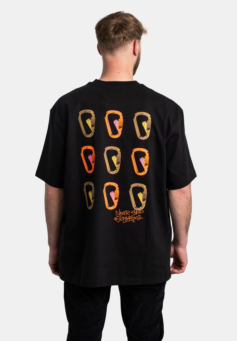 T-shirt nera in cotone con una grafica colorata di nove forme astratte sul retro e la scritta "NEVER STOP EXPLORING" in arancione.
