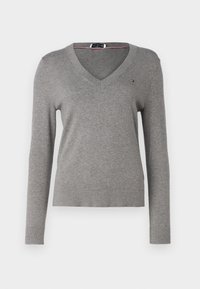 Sweater gris à manches longues avec un col en V, doté de bords côtelés aux poignets et à l'ourlet, et d'un petit logo sur la poitrine. Texture douce.