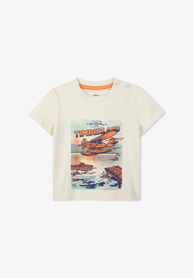 Korte mouw crèmekleurig t-shirt met een kleurrafgrafiek van een watervliegtuig en landschap, met oranje accenten rond de halslijn en knoopdetails.