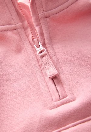 Indumento rosa chiaro con cerniera, realizzato in tessuto morbido. Presenta un design con mezza cerniera, una linguetta della cerniera con trama e dettagli cuciti lungo i bordi.