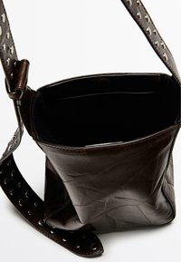 Brown leather shoulder bag with a textured finish, featuring a solid body and a studded strap for added detail. Open top design.