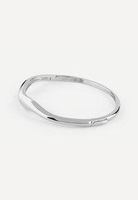 Srebrna bransoletka w kształcie gładkiego, zakrzywionego wzoru. Posiada polerowane wykończenie oraz subtelne zapięcie, zapewniające pewne noszenie.