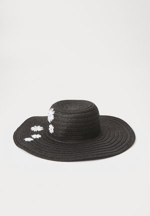 Sombrero de paja de ala ancha y negra con copa redonda y adornos florales de margaritas blancas a un lado. Acabado texturizado en todo el sombrero.