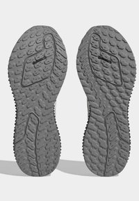 Suole di scarpe da ginnastica grigie con un motivo a scanalature robusto, caratterizzate da gomma testurizzata per una migliore aderenza e un logo Continental impresso su una delle suole.