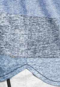 Kortærmet skjorte med et farveblokeringsdesign i nuancer af blå og grå, lavet af tekstureret stof med en rund kant og synlige sømme.