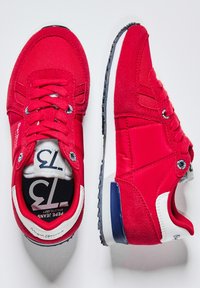 Sneaker sportive rosse che presentano un mix di materiali in tessuto e scamosciato, punta tonda, suola intermedia bianca e dettagli blu sul tallone.