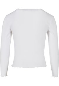 Bílý žebrovaný top s dlouhým rukávem s volánkovými lemy na spodním okraji a manžetách, zobrazený zezadu.