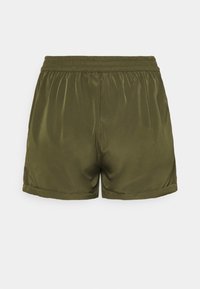 Short taille élastique vert olive avec un tissu lisse et des ourlets pliés, montré de dos sur un fond clair uni.