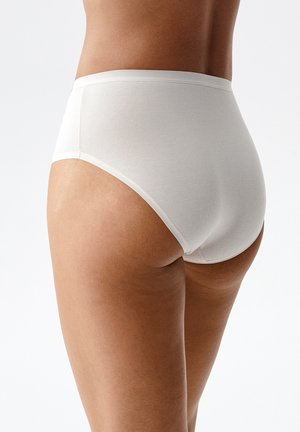 Widok z tyłu osoby noszącej proste białe bawełniane bieliznę, ukazujący dopasowanie i teksturę tkaniny na jasnej skórze.