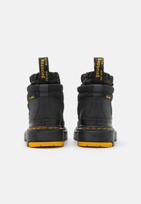 Juodi auliniai batai su paminkštintu apykakle, geltonais akcentais, guminiais padais ir traukimo juostelėmis su užrašu "Bouncing". Tekstūruotas paviršius.