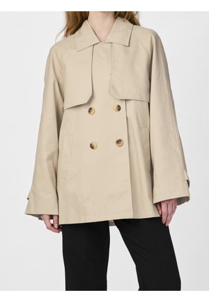 Gabardina beige de doble botonadura con cuello ancho, usada sobre pantalones negros, mostrada desde la mitad del muslo hasta el cuello en una persona de pie.