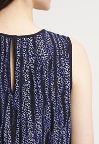 Ärmelloses Oberteil mit einem Schwarz-Blauen Leopardenmuster, das eine Schlüssel-Ausschnitt-Rückenpartie und einen glatten, leichten Stoff aufweist.